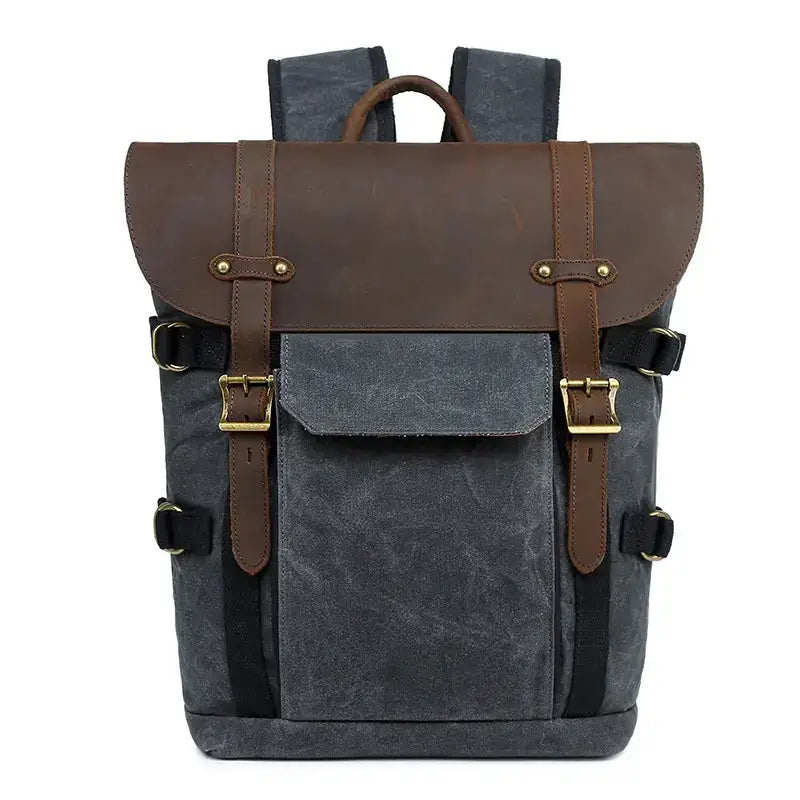 Dark gray canvas backpack with brown leather accents and gold-tone buckles.