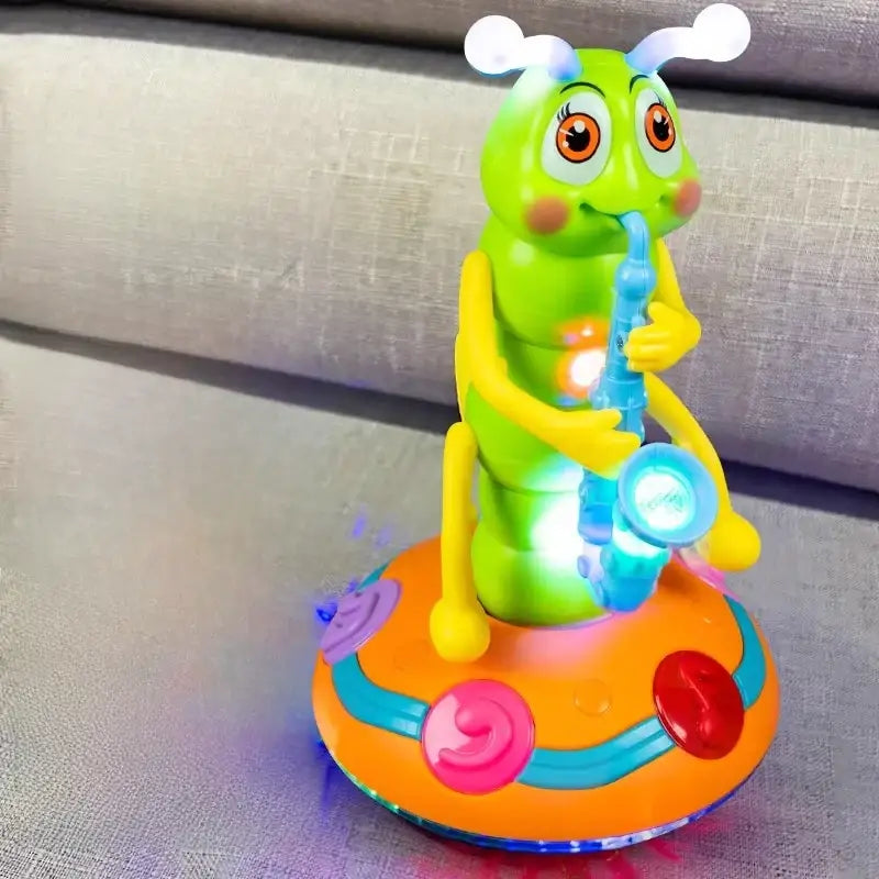A green, cartoonish caterpillar toy with yellow limbs and antennae is playing a blue saxophone on an orange, circular base adorned with colorful buttons.