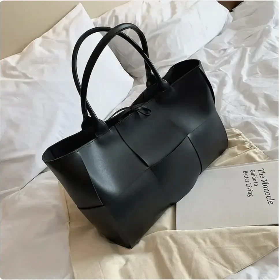 Black leather tote bag with structured panels and top handles.