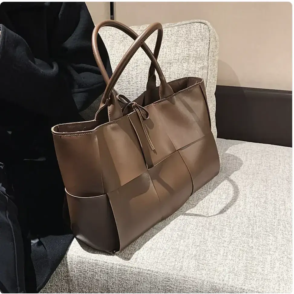 Brown leather tote bag with a woven panel design and top handles.