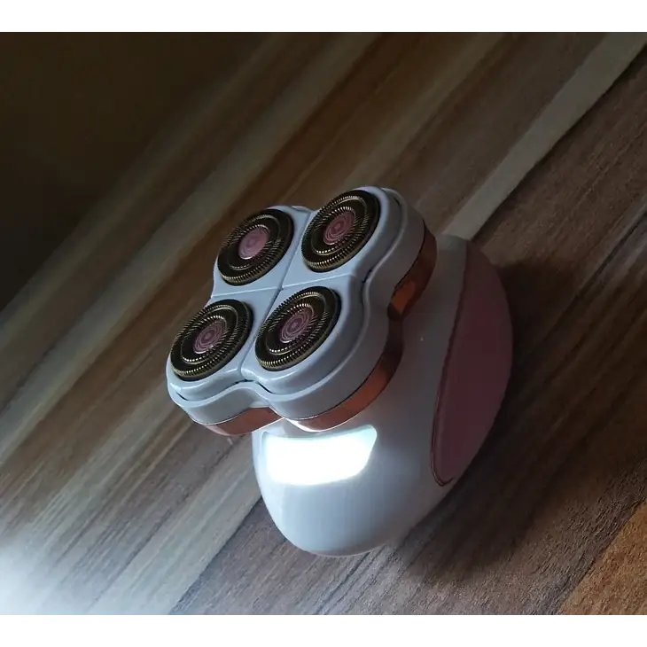 Pink and white electric razor with four rotary heads.