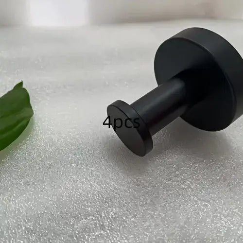 Black matte-finished metal door stopper with a cylindrical body and flat circular ends.