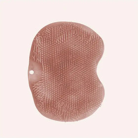 A soft, rose-gold silicone bath brush with a textured surface of fine bristles.