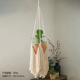 Cream-colored macrame hanging plant hanger with a terracotta pot suspended from its woven cords.