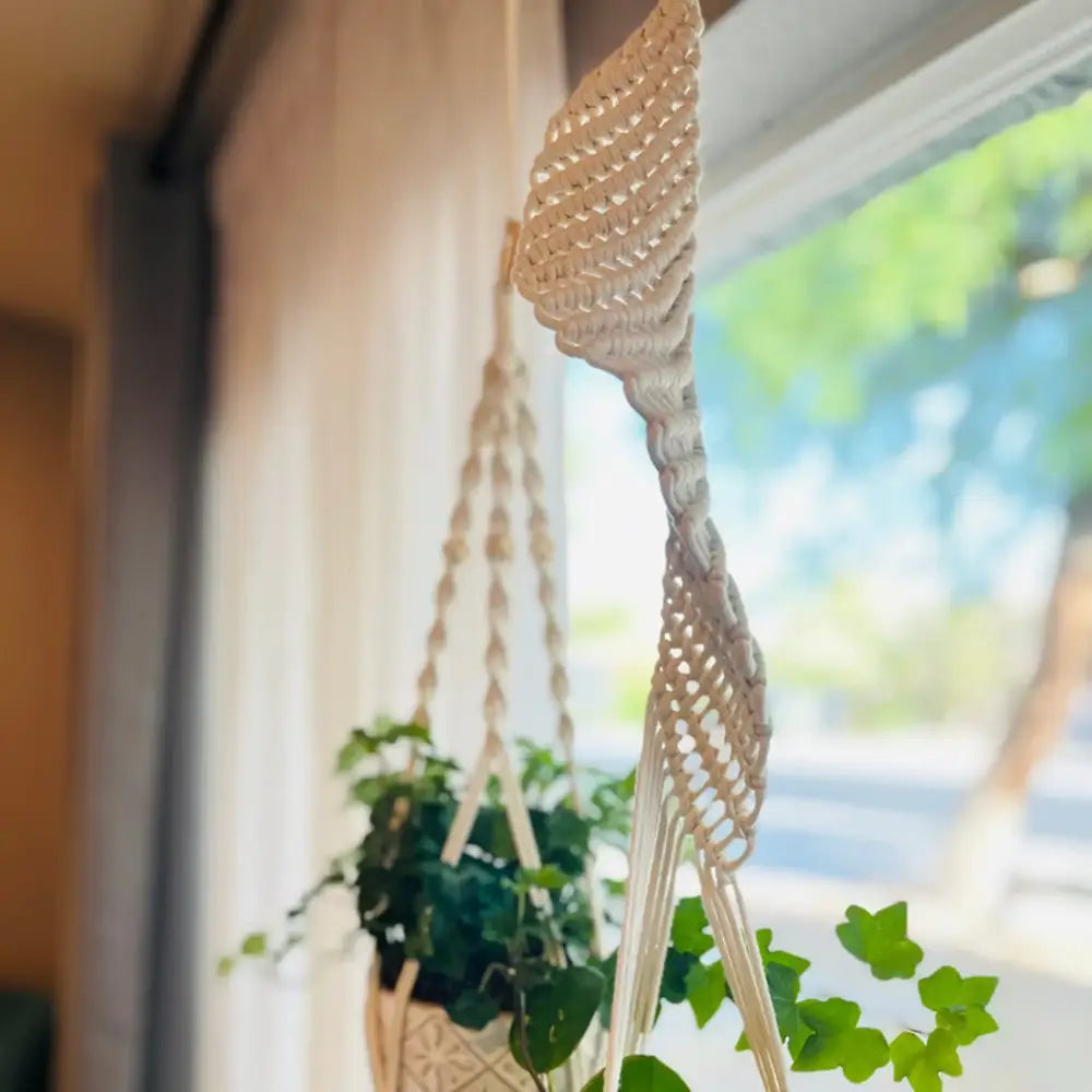 Beige macrame plant hanger with intricate woven patterns and a braided central design.