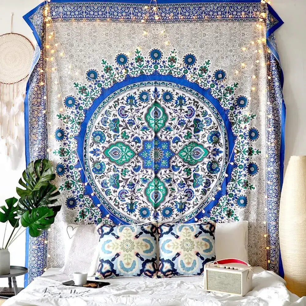 A vibrant blue and green mandala tapestry with intricate floral patterns, hanging as a decorative wall piece.