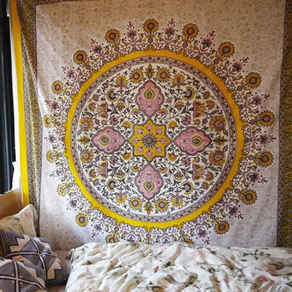 A vibrant, circular mandala tapestry with intricate floral and geometric patterns in shades of pink, yellow, gold, and cream hangs on a wall.