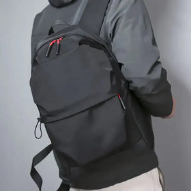 Black nylon backpack with red zipper pulls and a sleek, minimalist design.