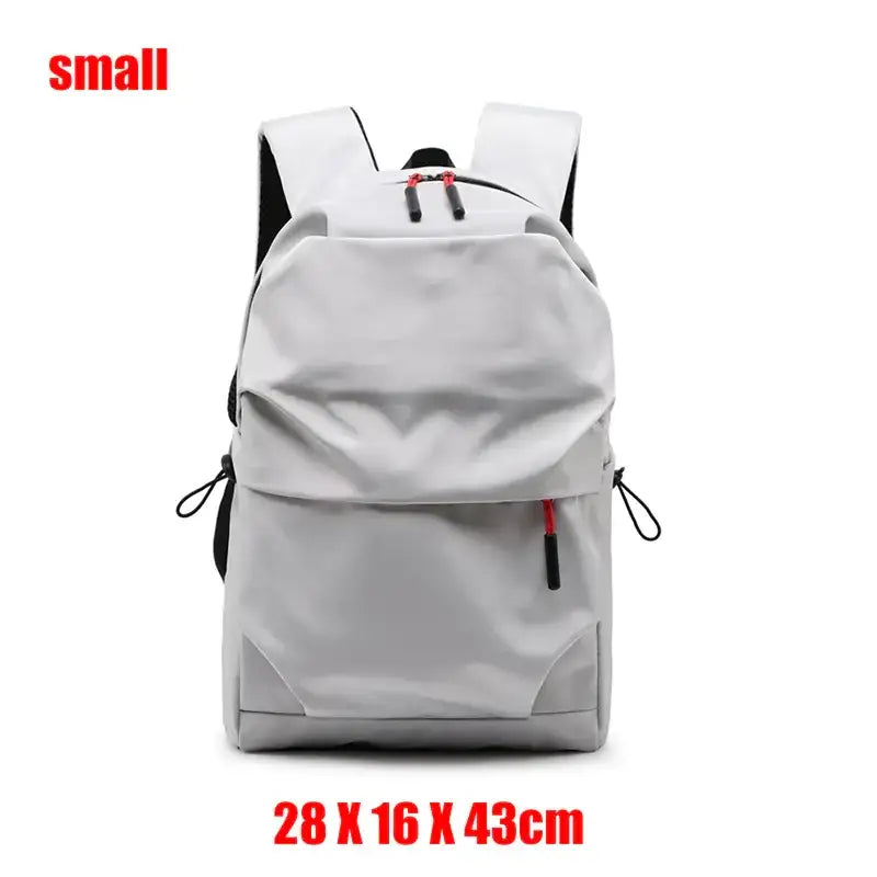A sleek, small gray backpack with black straps and red zipper pulls.