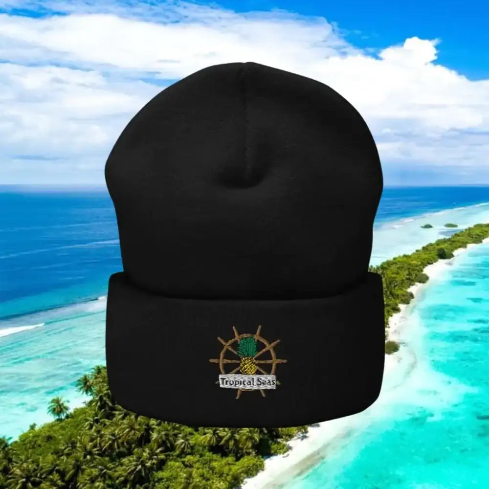 Black knit beanie featuring an embroidered tropical-themed logo with a pineapple and ship’s wheel.