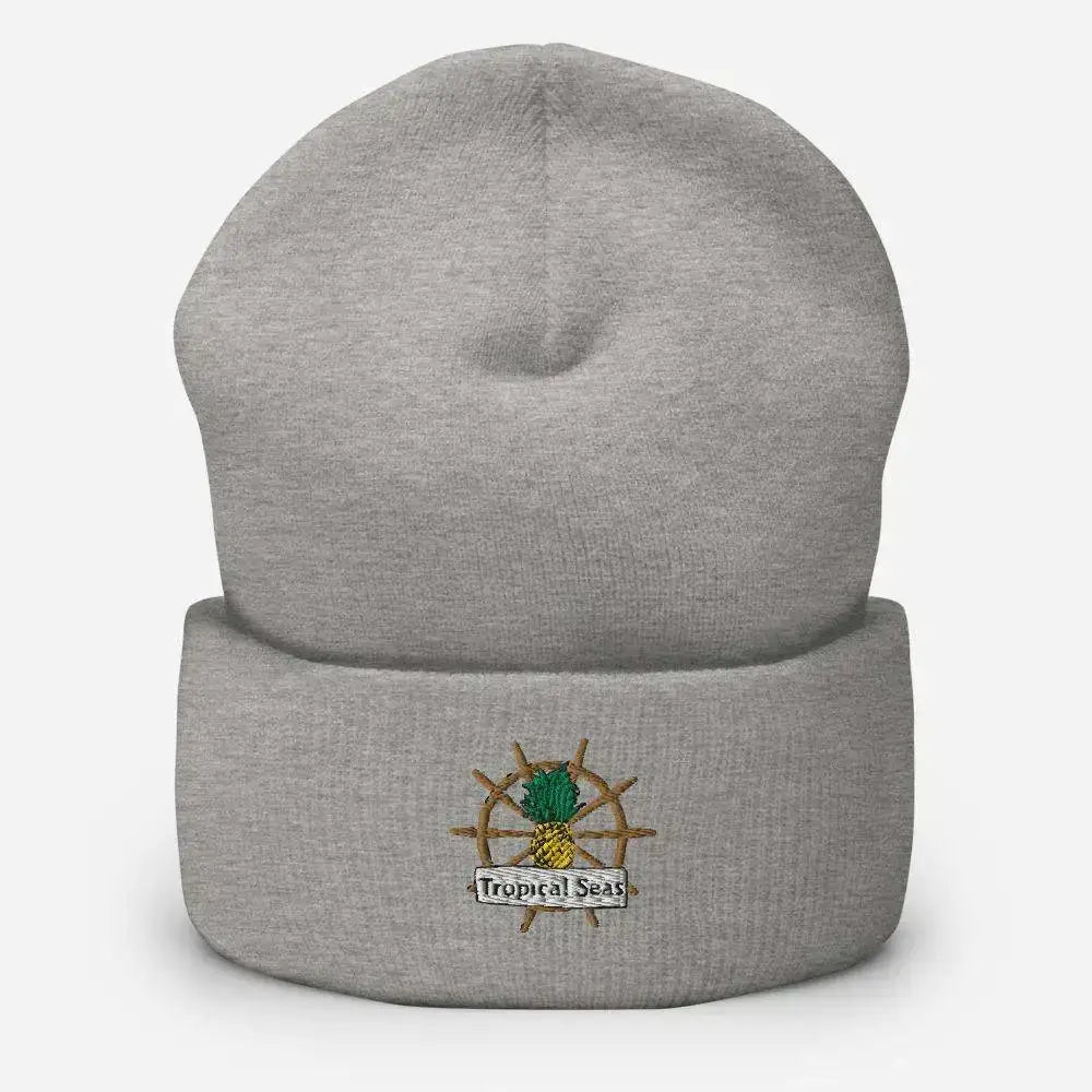 Gray heathered knit beanie with a embroidered pineapple on ship’s wheel design and ’tropical seas’ text.