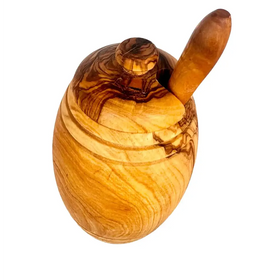 Handcrafted olive wood honey pot with a matching lid and integrated spoon, featuring natural grain patterns in warm golden-brown tones.