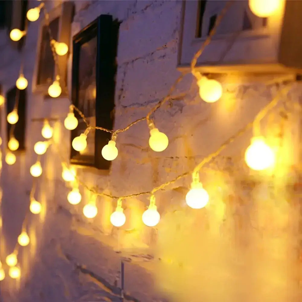 Warm yellow globe-shaped string lights strung along a rustic wall.