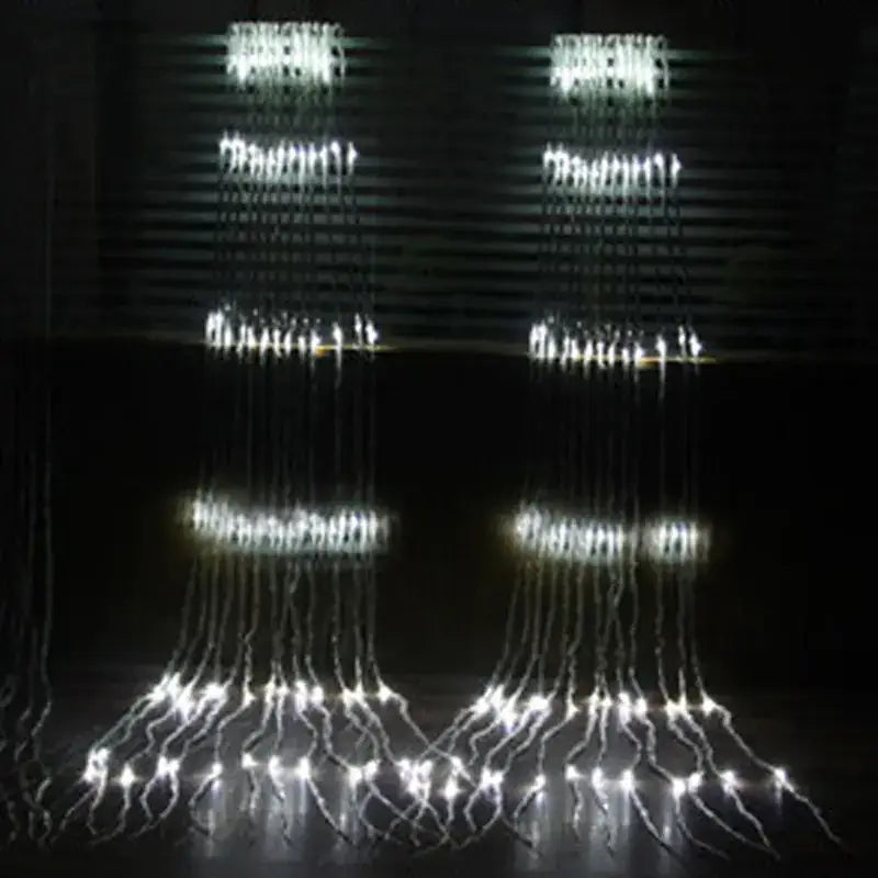 Two illuminated led waterfall light displays, each featuring cascading strands of bright white lights arranged in a tiered pattern against a dark background.