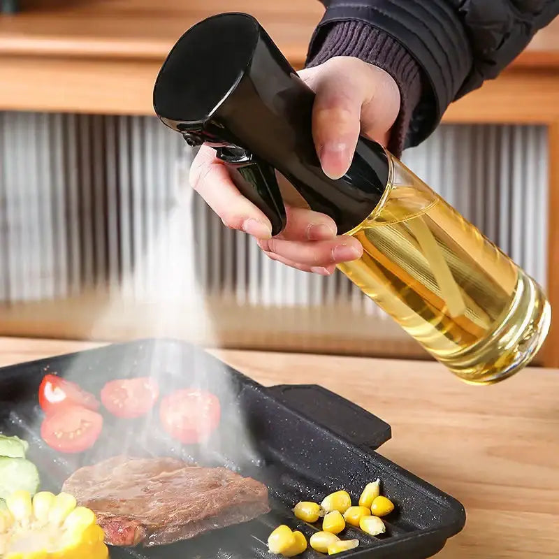 Black and clear glass oil sprayer with a black nozzle, designed for precise cooking spray application.
