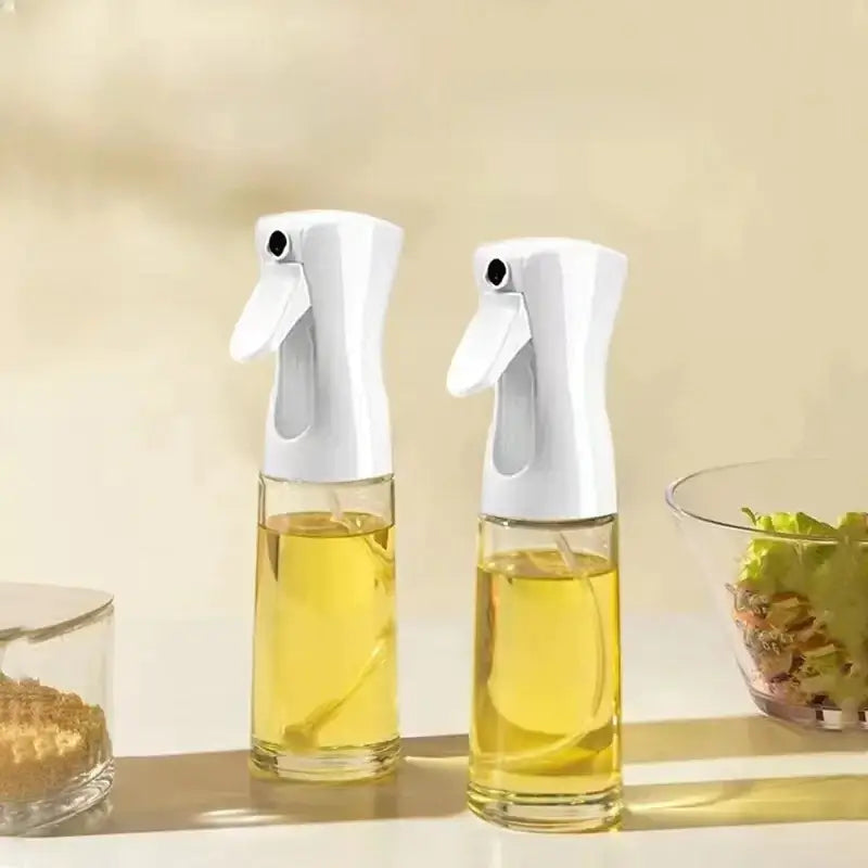 Two identical white spray bottles with clear glass bodies filled with golden-yellow liquid, designed for kitchen use.