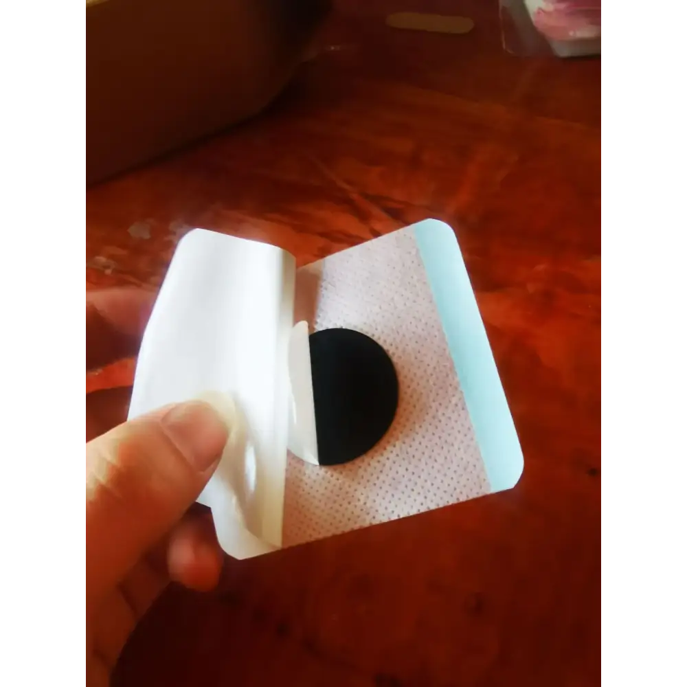 A white adhesive patch with a black circular pad and light blue edges, designed for therapeutic use.