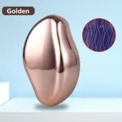 Golden metallic bean-shaped object with a smooth, reflective surface and subtle purple textured inset.