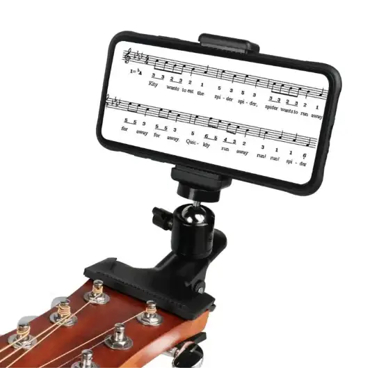 Black phone stand with adjustable clamp, designed to hold a smartphone displaying sheet music and securely attach it to the headstock of an acoustic guitar.