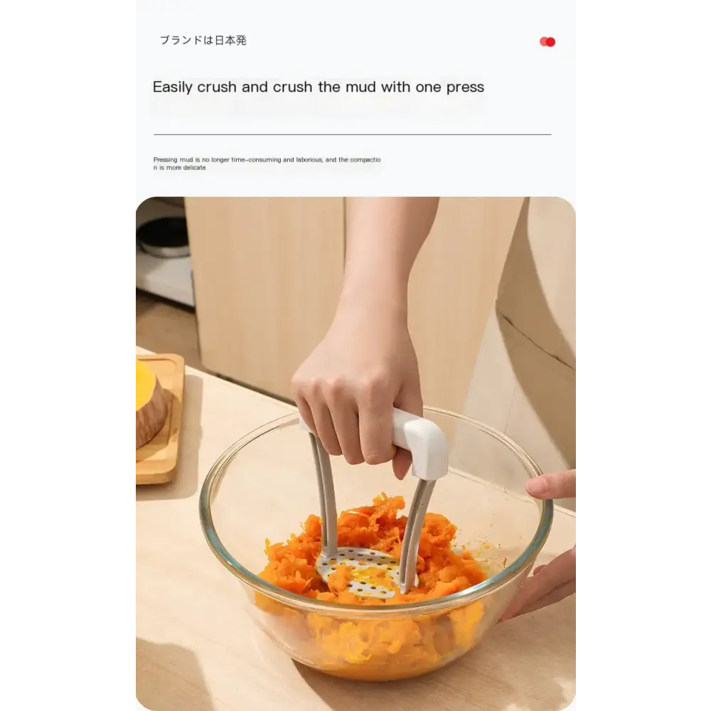 White-handled potato masher with metallic pressing arms and perforated base, shown crushing orange sweet potatoes in a clear glass bowl.