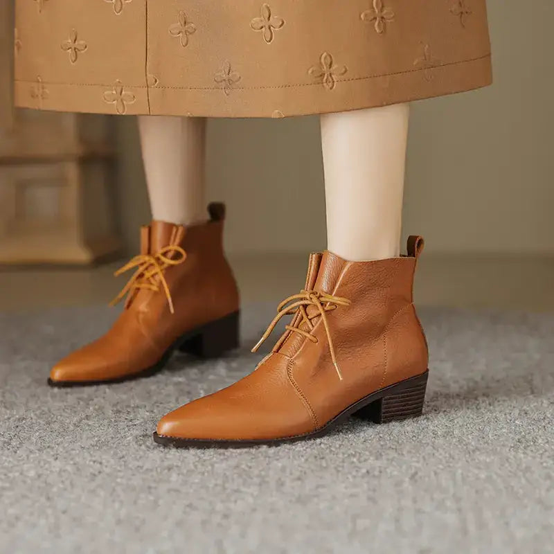 Tan leather ankle boots with a pointed toe and low block heel, featuring matching tan laces.