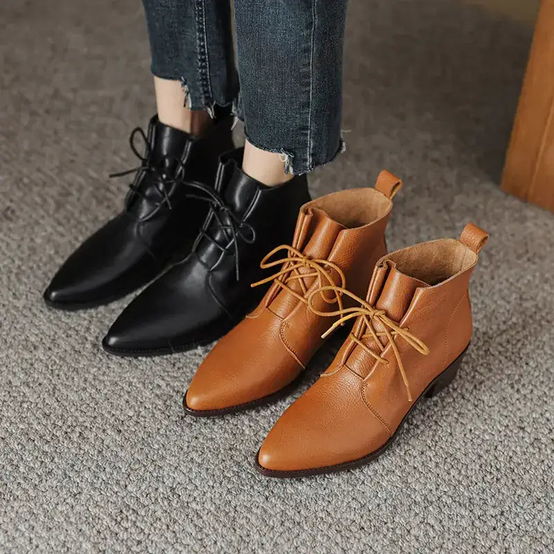 A pair of tan leather ankle boots with pointed toes and matching laces, alongside a black version.