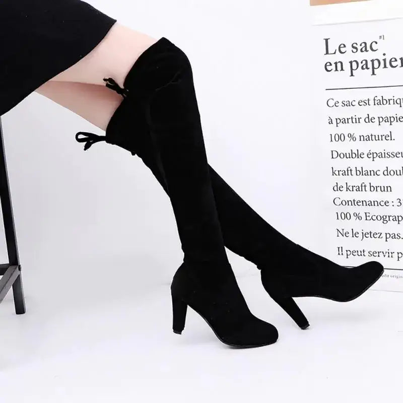 Black velvet over-the-knee boots with a high heel and tied ankle details.