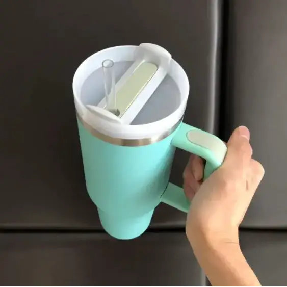 A mint green insulated travel mug with a white lid, silver rim, and matching handle.