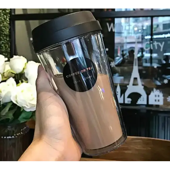 Clear double-walled travel tumbler with a black lid and a circular label that reads ’coffee or tea 20oz’.