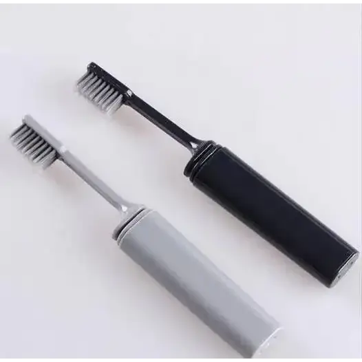 Two compact travel toothbrushes, one black and one gray, with sleek plastic handles and soft bristles.