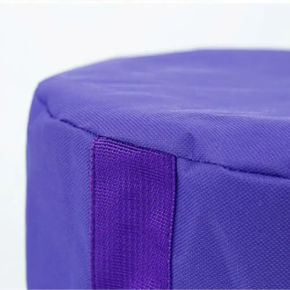 Purple fabric meditation cushion with a stitched seam and a matching purple strap along its side.