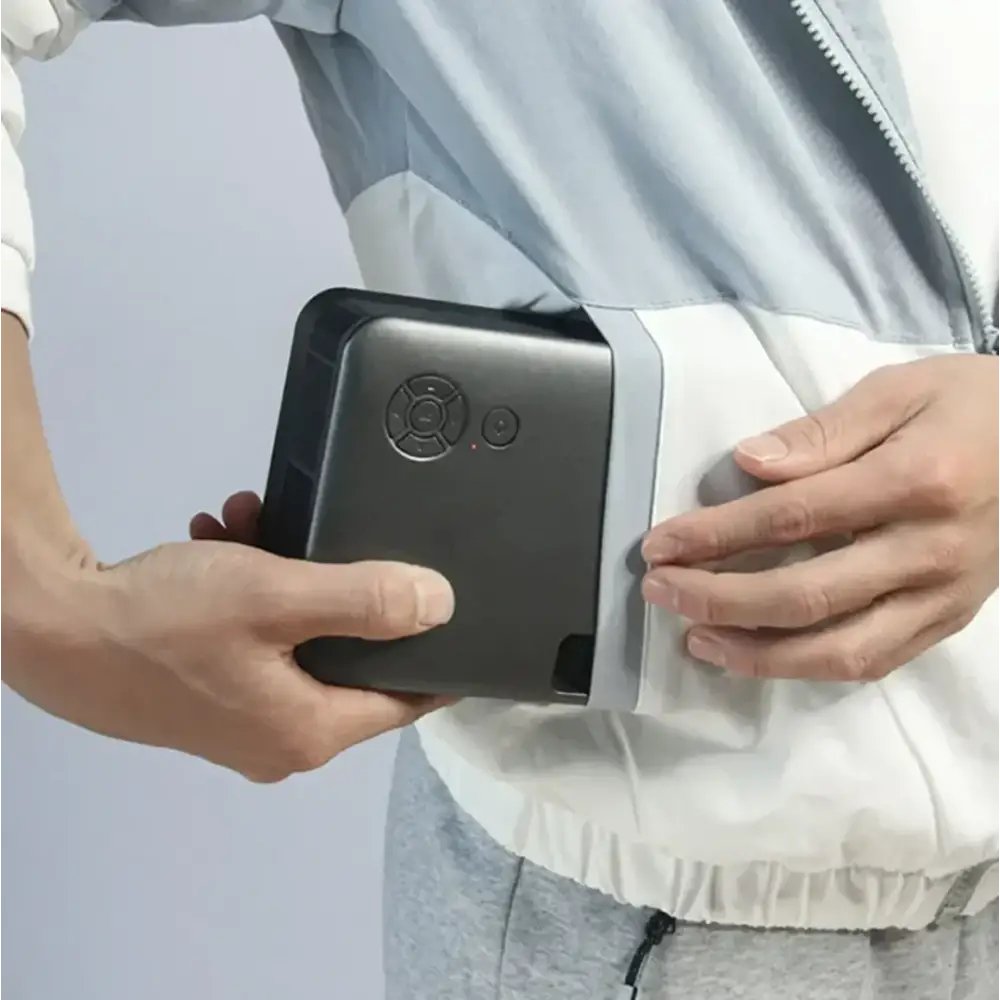 Black rectangular portable projector with circular control dial and small button on top surface
