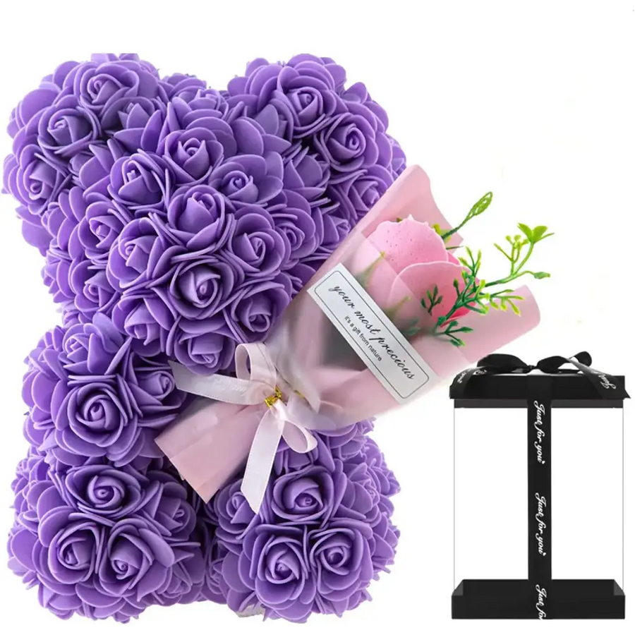 Purple rose-covered bear crafted from foam, wrapped with a pink ribbon and accompanied by a small bouquet of artificial flowers in a gift box.