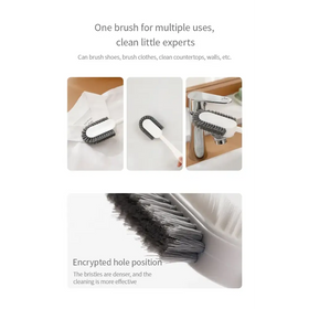 Multi-purpose cleaning brush with a white handle and dense gray bristles, designed for versatile use on shoes, clothes, countertops, and walls.