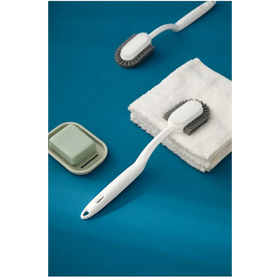 White plastic dish brush with gray bristles and a looped handle.