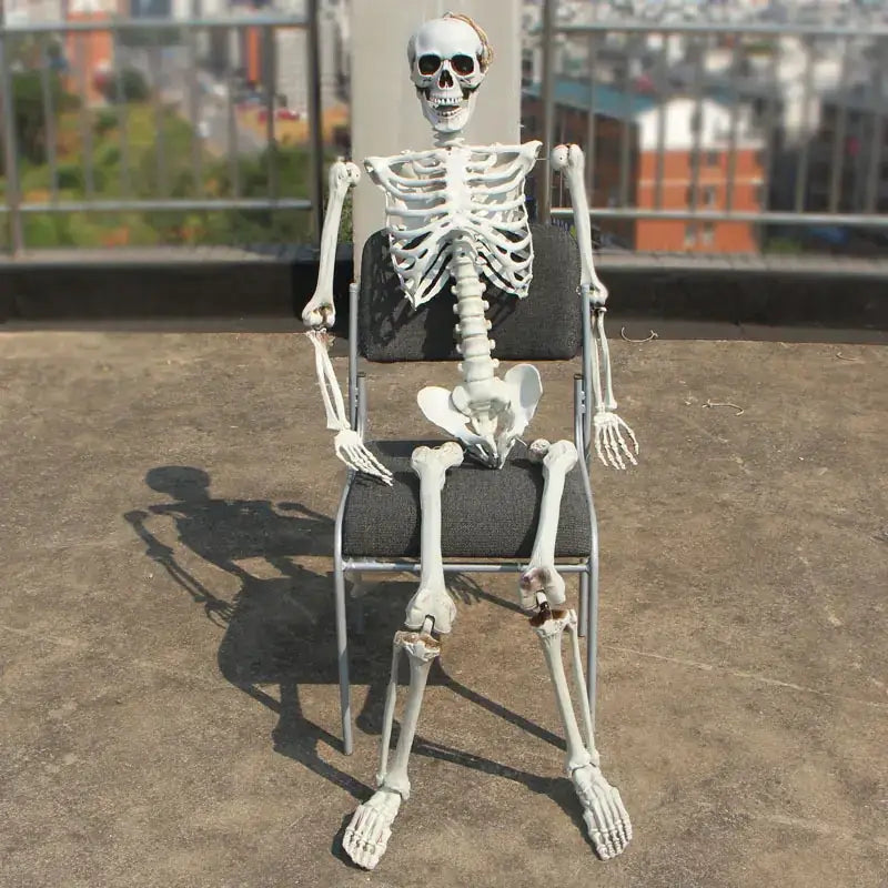 A white plastic skeleton figurine seated in a folding chair.