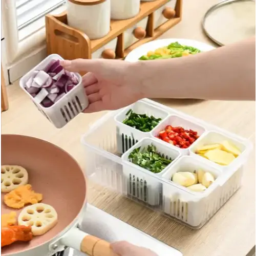 Clear plastic compartmentalized kitchen organizer with white dividers holding chopped vegetables.