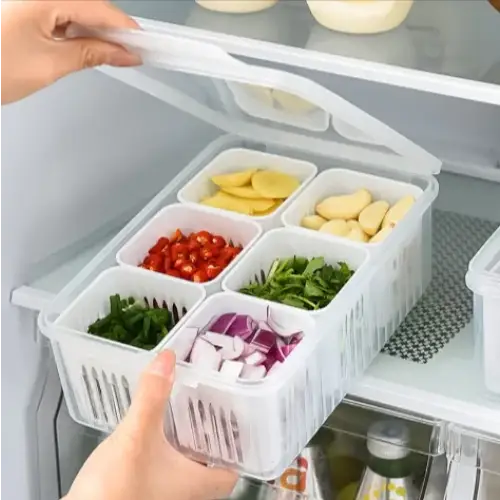 White plastic refrigerator organizer with six compartments, each holding different chopped vegetables.
