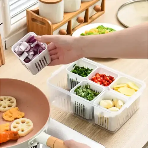 White plastic segmented kitchen storage container with slotted compartments holding chopped vegetables