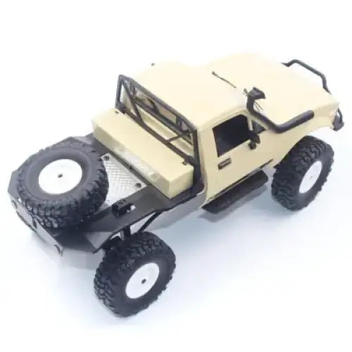 Beige and black remote-controlled off-road truck with rugged tires, a spare tire mounted on the rear bumper, and detailed interior features.