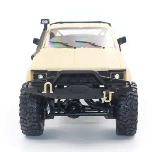Beige remote-controlled off-road truck with black rugged tires, a black front bumper featuring gold-colored hooks and a roof-mounted light bar.