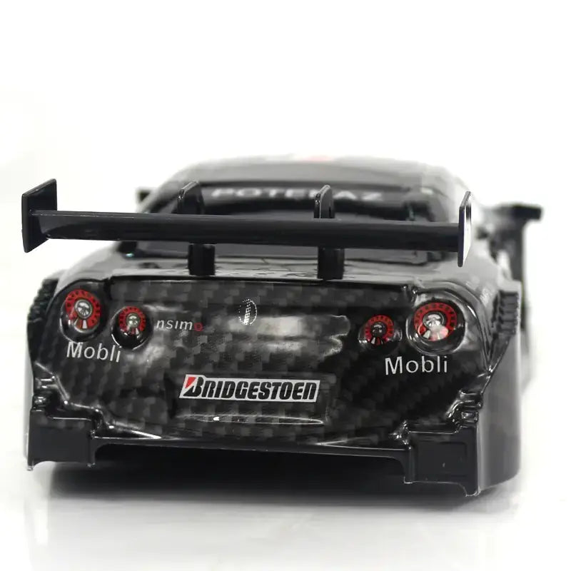 Black carbon fiber finish model of a nissan gt-r with red taillights and bridgestone decals.