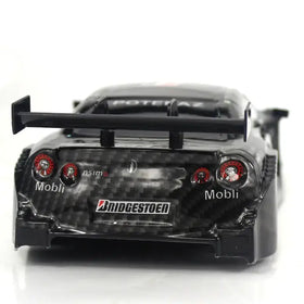 Black carbon fiber finish model of a nissan gt-r with red taillights and bridgestone decals.