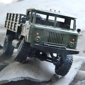Olive green metal rc truck model with rugged off-road tires and detailed grille.