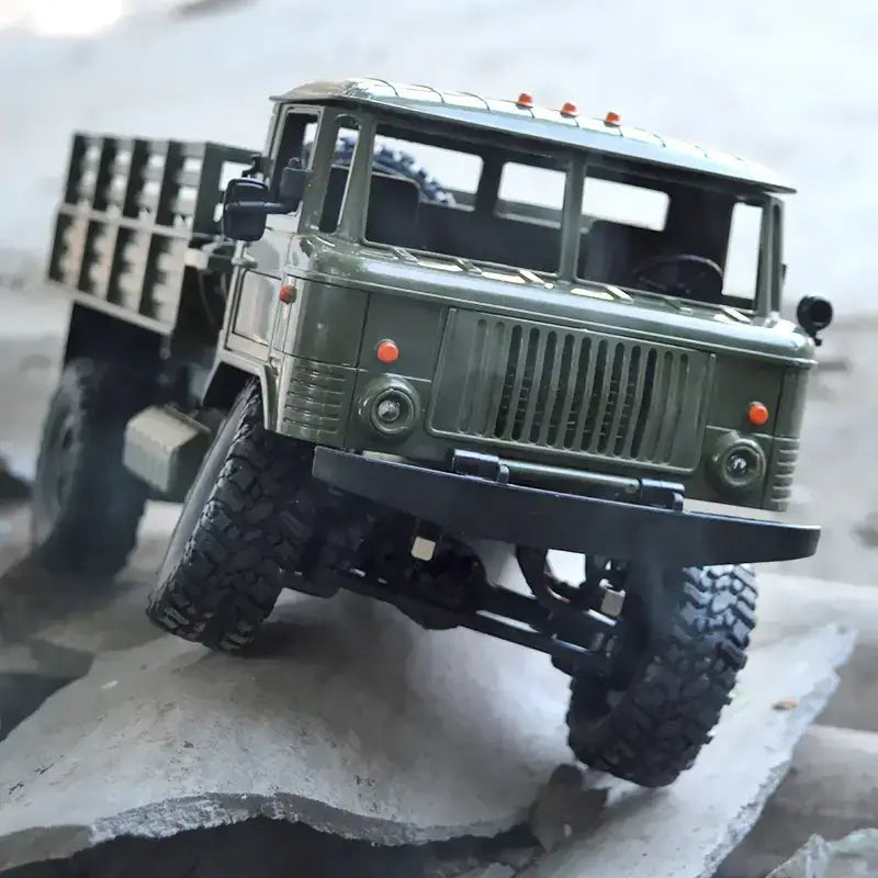 Olive green metal rc truck model with rugged off-road tires and detailed grille.