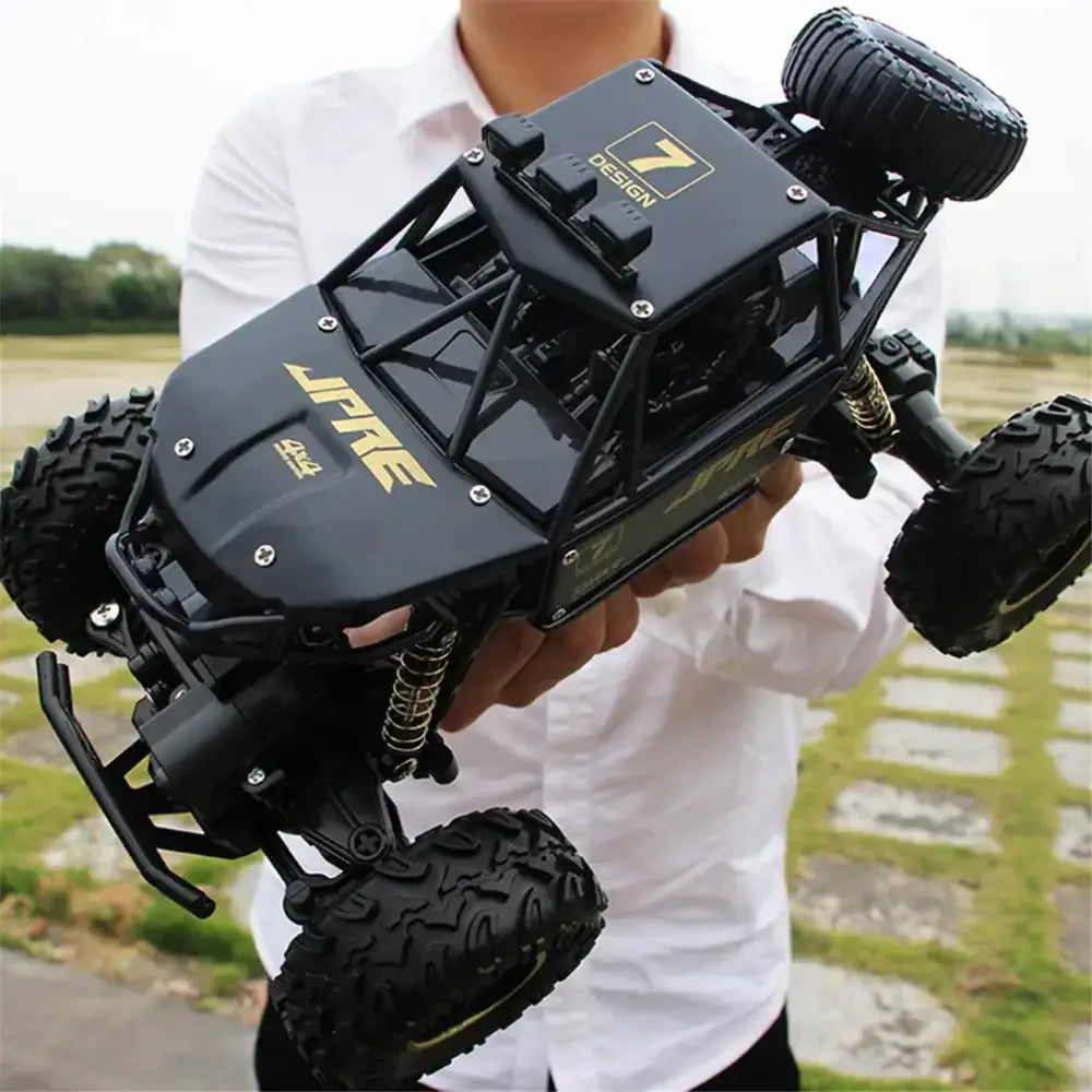 Black and gold jpre 4x4 remote-controlled off-road truck with rugged tires and a detailed chassis.