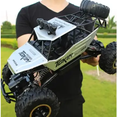 White and black remote-controlled off-road truck with rugged tires and a detailed chassis.