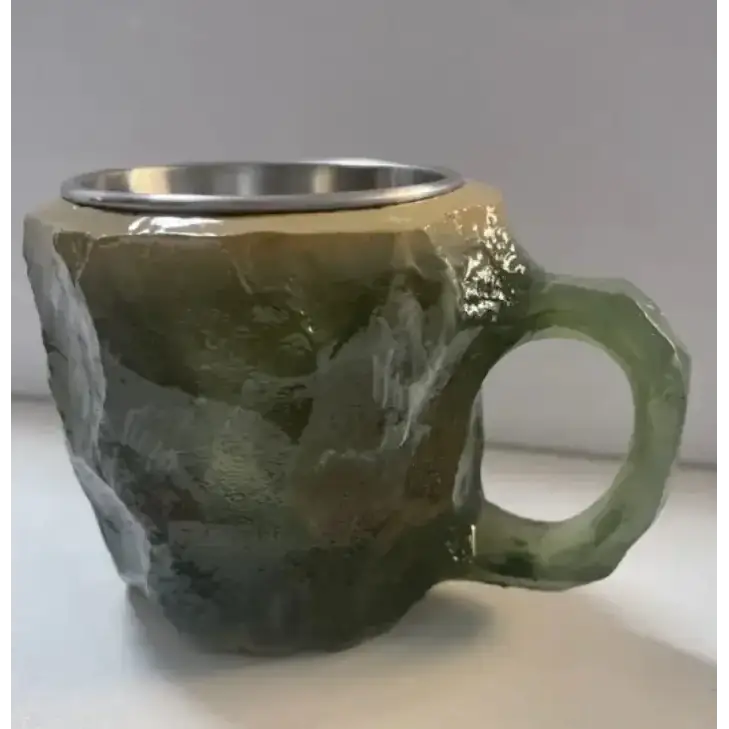 Rough-textured green ceramic mug with a metallic silver interior and handle.