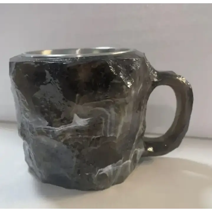 Rough-textured dark gray stone mug with a metallic silver rim and handle.
