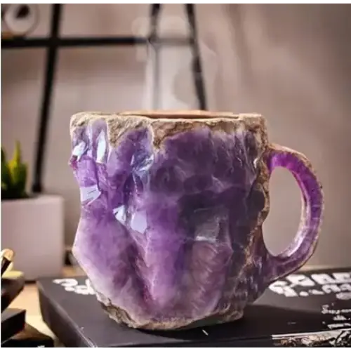 A rustic, handcrafted purple amethyst geode mug with a natural, jagged edge and earthy brown base.